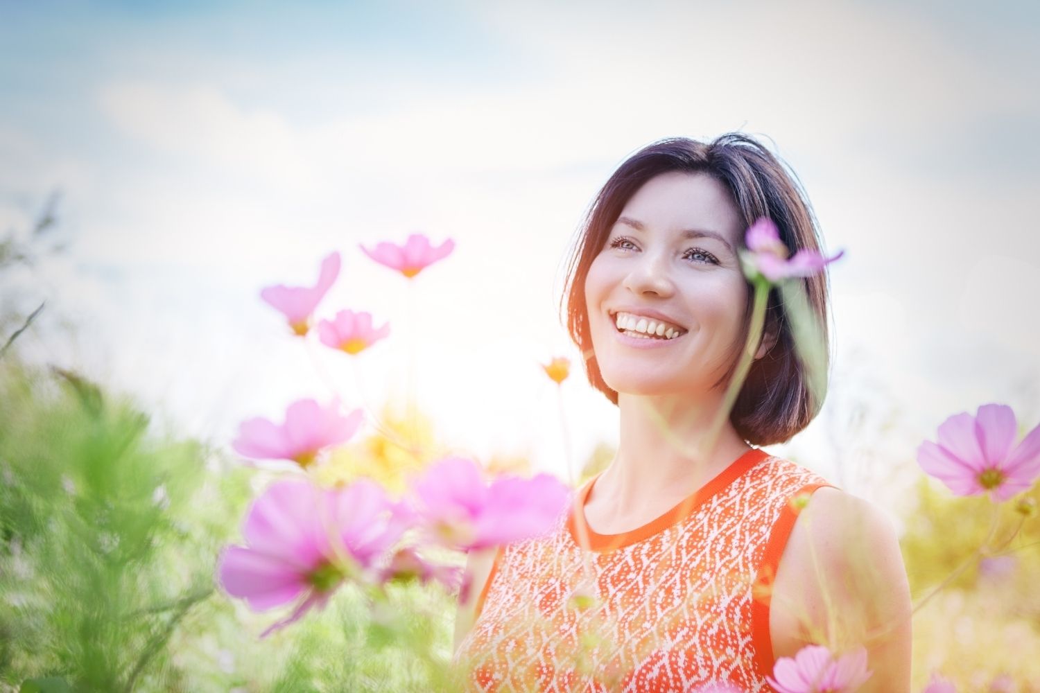 A smiling woman looking up, enjoying nature, illustrating feelings of rejuvenation from IV nutrition.