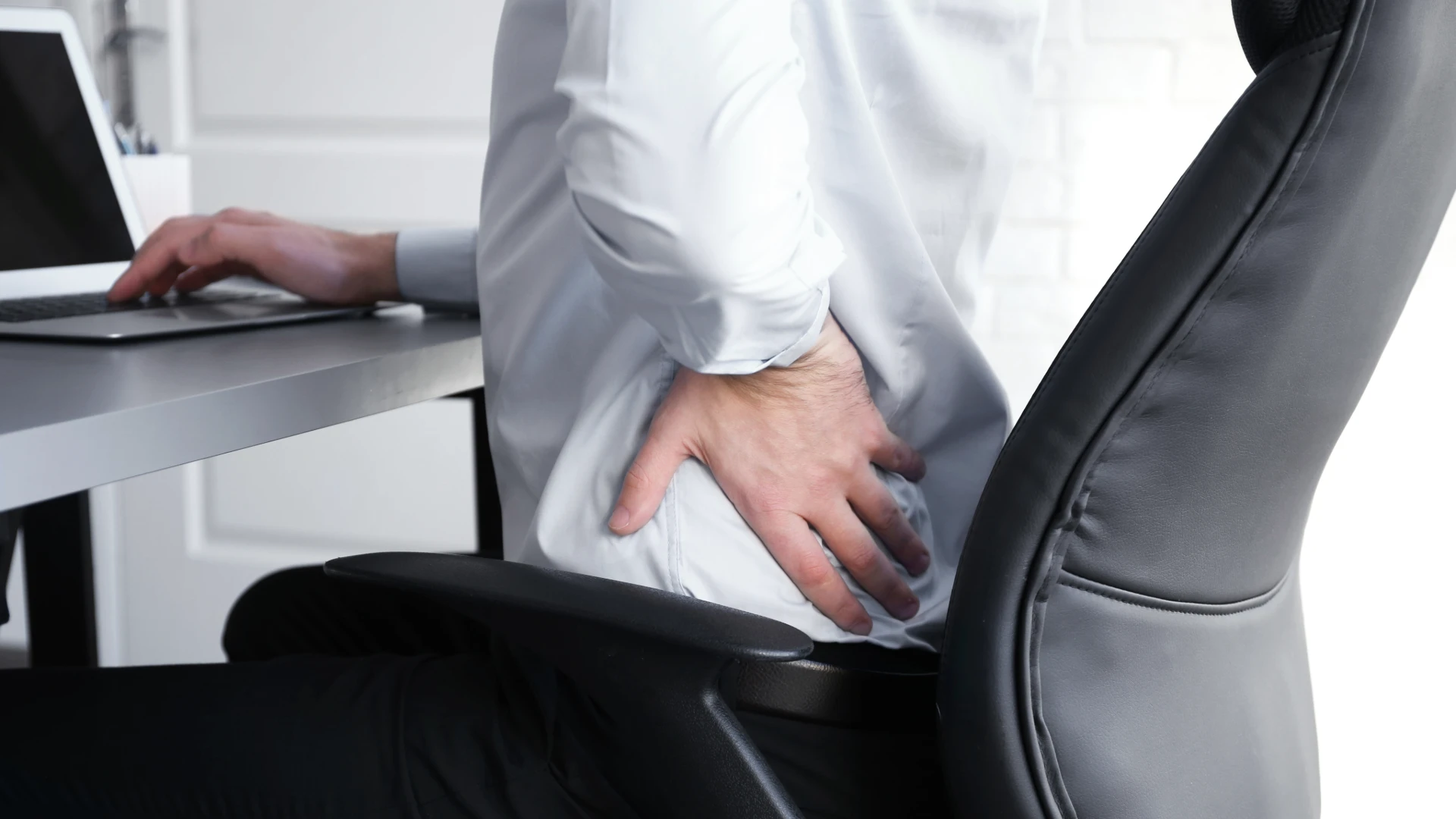 person suffering from low back pain sitting at a desk